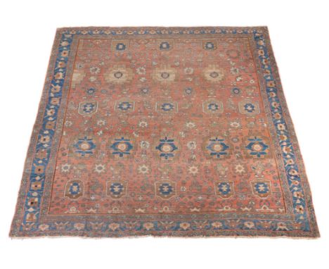 A Bakshaish carpet, the madder field decorated with an overall design incorporating rows of stylised foliate motifs, within a