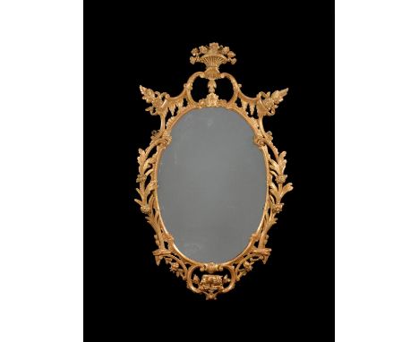 A George III oval wall mirror, circa 1770, in the manner of Thomas Chippendale, the pierced frame carved with rocaille and fl