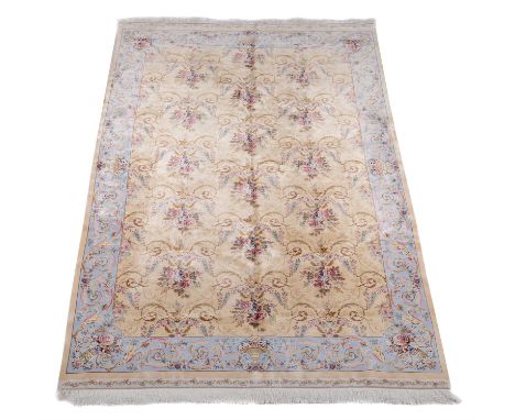 A Qum silk carpet,  of French inspired style, the pale field decorated with an overall design of flowers within scroll framed