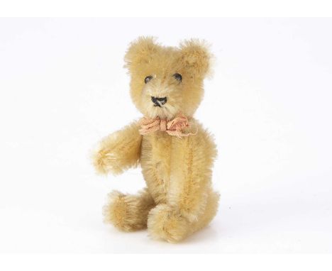 A post war miniature Schuco teddy bear, with blonde mohair, black pin eyes, black stitched nose and mouth, swivel head and me