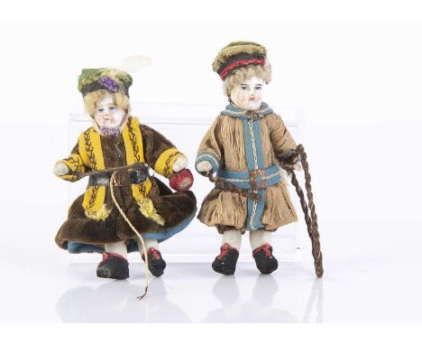 Two early mid 19th century all-bisque dolls’ house dolls playing with toys, with white bisque, painted features with rosy che