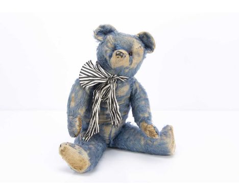 A 1920s British blue mohair teddy bear, with orange and black replacement glass eyes, black stitched nose and claws, pronounc