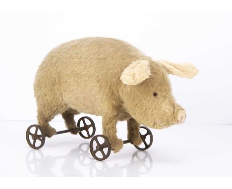 An early German mohair pig on wheels 1910-20s, probably Steiff, pink mohair, replaced glass eyes, knotted tail, stood on meta