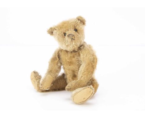 An early Steiff teddy bear circa 1909, with blonde mohair, black boot button eyes, pronounced muzzle, black stitched nose, mo