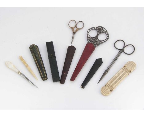 A 19th century ornate cut steel sewing scissors, marked BT, in red leather sleeve; a mother of pearl and steel stiletto; two 