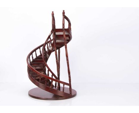 A recent wooden spiral staircase doll or shopwindow display stand, red varnished, with turned balusters and sweeping handrail