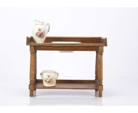 A dolls’ washstand 1930s, of light oak with continental porcelain, continental porcelain jug, basin and slop bucket —9 1/2in.