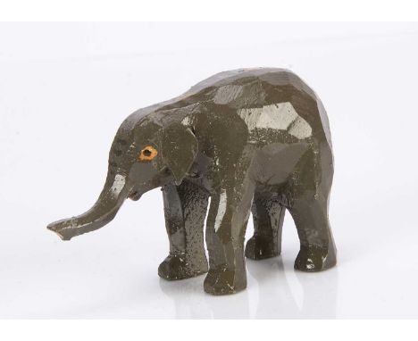 A Forest Toys of Brockenhurst baby elephant, carved and grey painted wood with raised trunk —4 1/2in. (11.5cm.) long