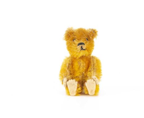 A miniature Schuco teddy bear 1920s, with golden mohair, black pin eyes, black stitched nose and mouth, metal framed jointed 