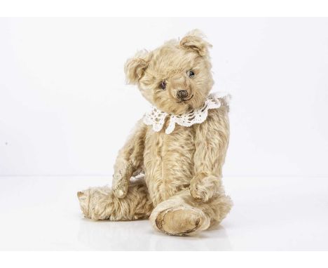 A 1920-30s Chiltern teddy bear, with blonde mohair, clear and black glass eyes with remains of painted backs, clipped muzzle,