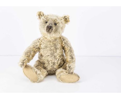 An early Steiff Teddy Bear circa 1910, with rare brown mohair now faded to blonde, black boot button eyes, pronounced clipped