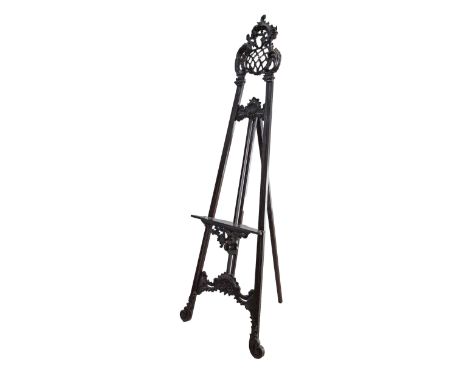 A Victorian mahogany Picture Easel / artist picture stand, carved with acanthus leaves and a cocoa cresting with a lattice ce