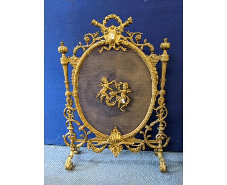 A late 19th Century French brass firescreen in the Rococo style with winged cherubs centred on a gauze, 88cm H x 67cm W. Loca
