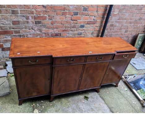 A good quality reproduction of a Regency mahogany breakfront sideboard with four drawers and four doors, on splayed bracket f