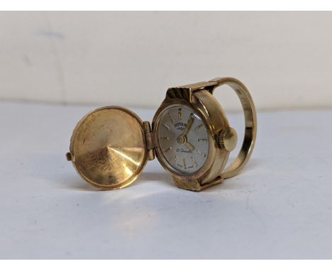 A vintage 9ct gold novelty watch ring having a hinged top opening to reveal the silvered dial, total weight 8.2g 