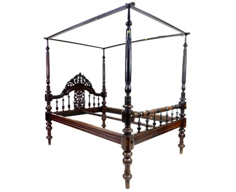 A 19th century mahogany four poster bed, with foliate carved and pierced arched headboard, the footboard with turned seven sp