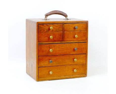 A mid 20th century portable bank of four over three drawers for small tools or parts, with single leather handle to its top, 