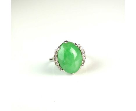 A jade and diamond ring, designed as an oval jade cabochon claw set in white metal within diamond set shoulders, the white me
