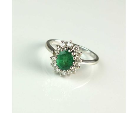 An 18ct gold emerald and diamond oval cluster ring, designed as a central oval mixed cut emerald claw set within a border of 