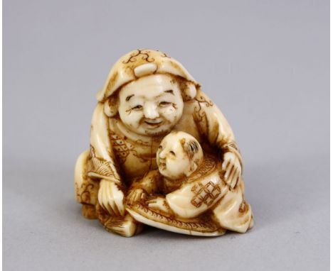 A JAPANESE MEIJI PERIOD CARVED IVORY NETSUKE OF HOTEI, one of the seven luck gods, seated with a snamm boy crawling upon his 