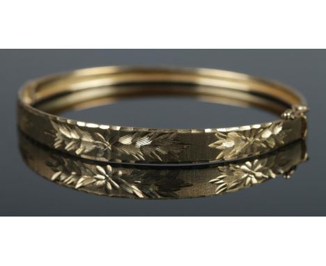 A 9ct gold bangle featuring floral decoration. 5.39g.  