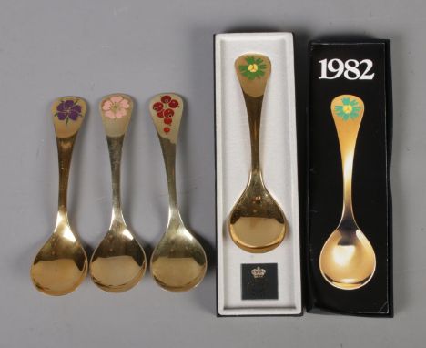 Four Georg Jensen silver gilt year spoons featuring floral enamel decoration. Includes years 1974, 1976, 1982 (boxed) and 199