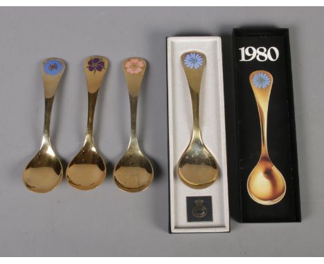 Four Georg Jensen silver gilt year spoons featuring floral enamel decoration. Includes years 1972, 1974, 1976 and 1980 (boxed