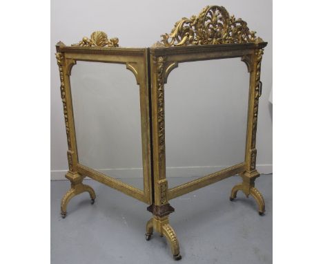 EARLY VICTORIAN HINGED, TWO SECTION, GILDED AND GESSO CARVED WOODEN FIRE SCREEN, with foliate pierced cresting, on outswept l