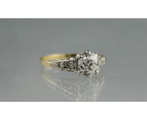 EARLY 20TH CENTURY DIAMOND SOLITAIRE RING.  The cushion cut diamond set in a high openwork scrolling mount set with two diamo