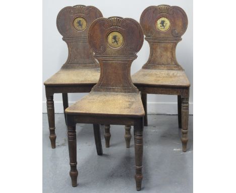 THREE EARLY 19TH CENTURY OAK ARMORIAL HALL CHAIRS with scroll moulded backs, having centre Lion passant armorial, solid seats