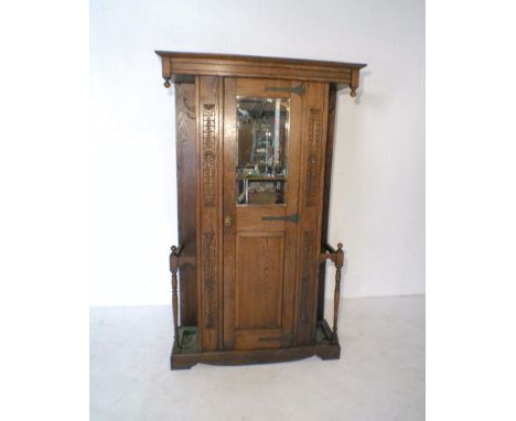 An oak single wardrobe with carved detailing, mirrored door and stick stands either side, length 112.5cm, height 182cm.