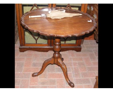 A 70cm diameter tripod table with shaped top and carved support