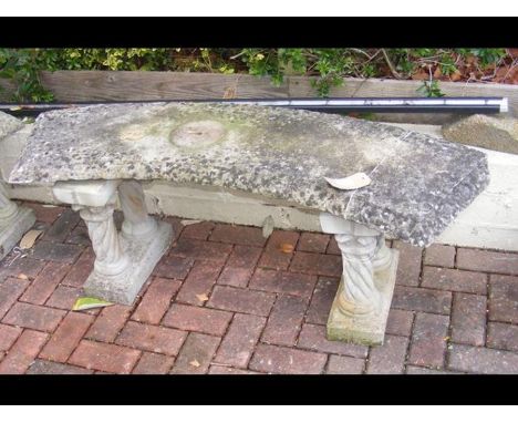 A curved concrete garden bench