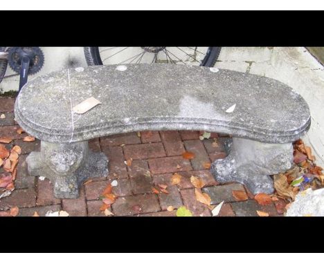 A curved concrete garden bench