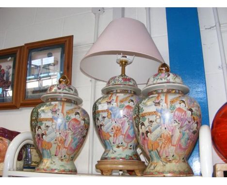 A reproduction Chinese Famille Rose table lamp and shade, together with the matching pair of lidded vases 