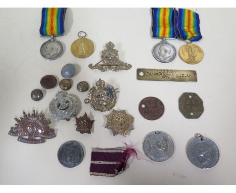 A collection of WWI medals and cap badges, including WWI Victory and War medals for 195306 SPR J.E Whitfield R E and two dog 