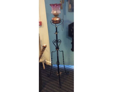 Wrought iron standard lamp with cranberry glass shade.