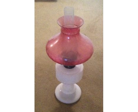 A white glass oil lamp with pink shade