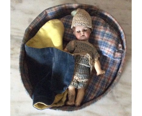 Small bisque headed doll in round bed