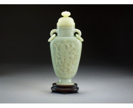 A Chinese celadon jade vase and cover, late Qing Dynasty, of flattened ovoid form with twin loop-and-ring handles, carved to 