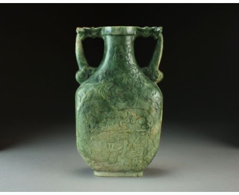 A large mottled green and white jade vase, late Qing Dynasty, of ovoid form with twin dragon handles, the body carved in reli