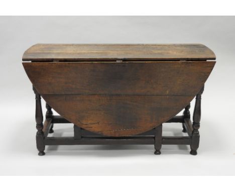 An early 18th century oak gate-leg dining table, the oval top reduced in diameter on slender baluster and bobbin turned suppo