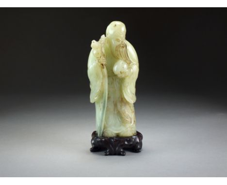 A Chinese jade figure of Shou Lao, late Qing/early Republic, modelled standing and holding his staff and a peach, with carved