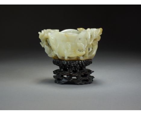 A Chinese grey-green jade libation cup, Qing Dynasty, carved as a lotus flower with buds and tendrils, with associated carved