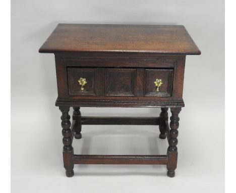 A 17th century style oak single drawer side table, the rectangular top over a geometrically moulded drawer front with brass d