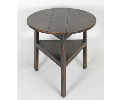 A George III oak cricket table, the circular three plank top on three out-swept legs united by a boarded shelf stretcher, 65.