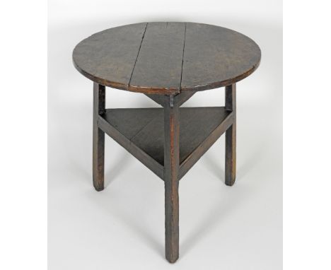 A George III oak cricket table, the circular three plank top on three out-swept legs united by a boarded shelf stretcher, 65.