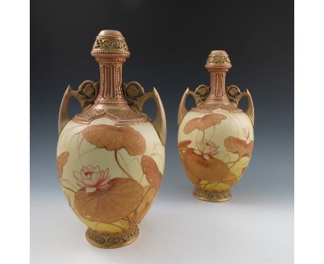 A pair of Royal Worcester blush ivory vases, with pierced tops, embossed necks, a pair of handles, the body decorated in the 