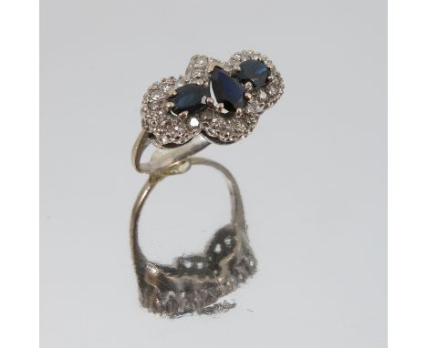 A sapphire and diamond triple cluster 18 carat gold ring, the central pendeloque cut sapphire flanked either side by oval cut