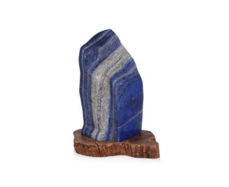A LARGE LAPIS LAZULI BOULDER SPECIMEN
Rectangular in form with grey banding and metallic-like inclusions, fitted hardwood sta